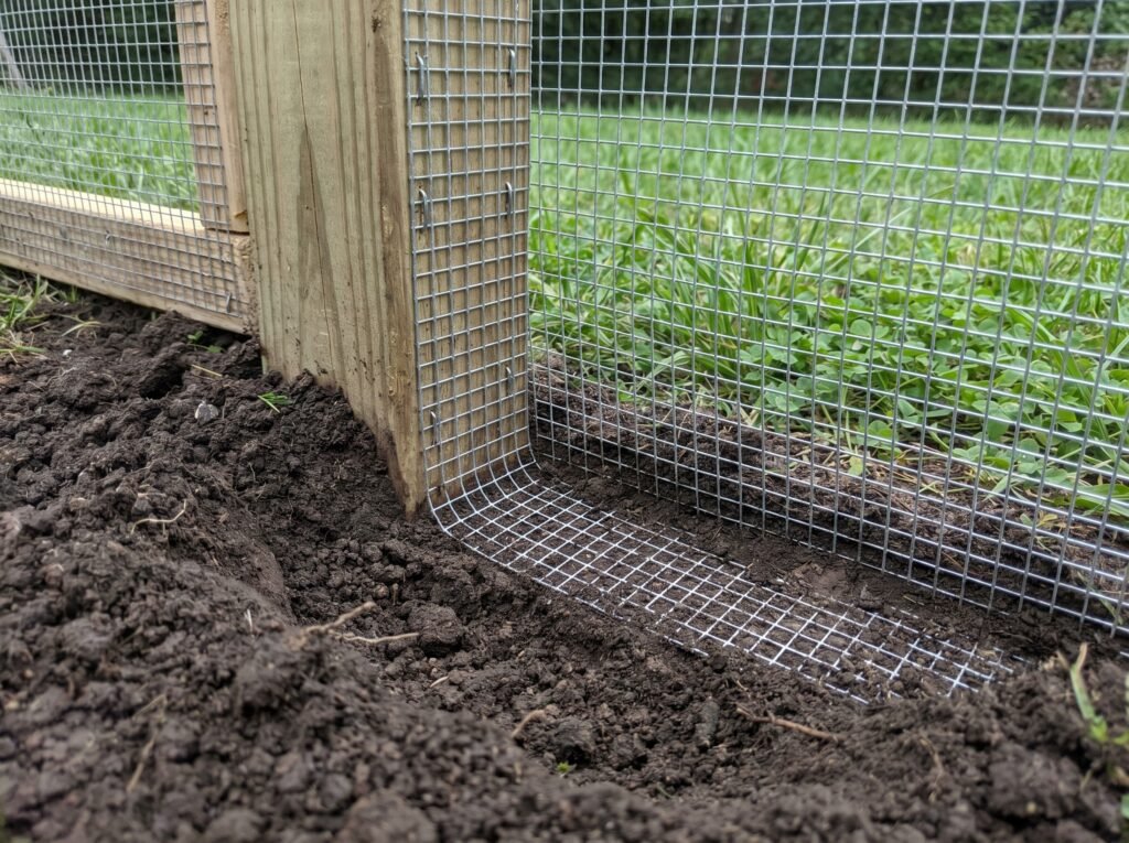 Hardware cloth apron buried in L-shape around large chicken coop run perimeter to stop diggers